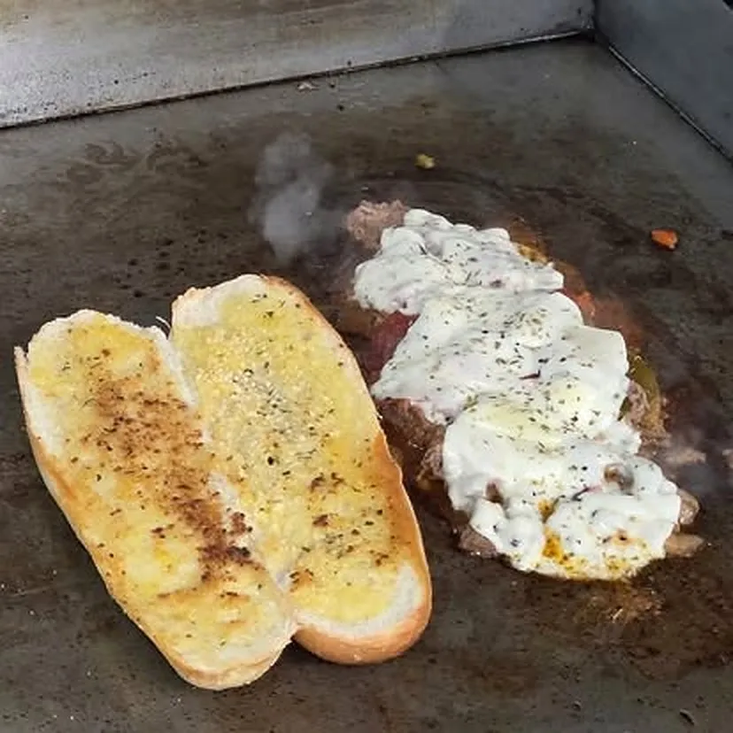 A Fat Freddy's Philly cheesesteak hot off the flat-top, melted cheese spilling over the toasted bun