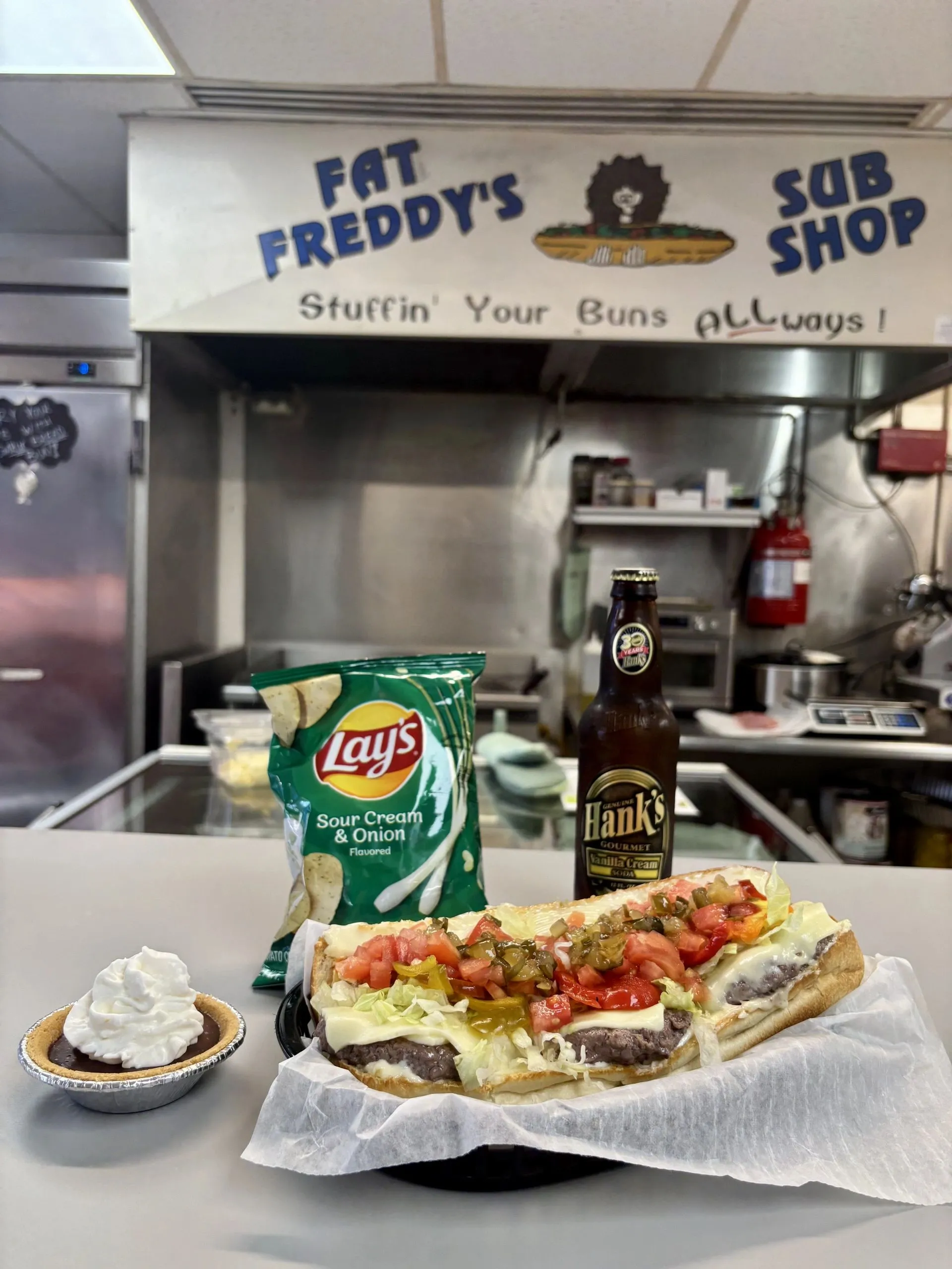 Behind the counter at Fat Freddy's — smash burger plated with chips and a cold beer