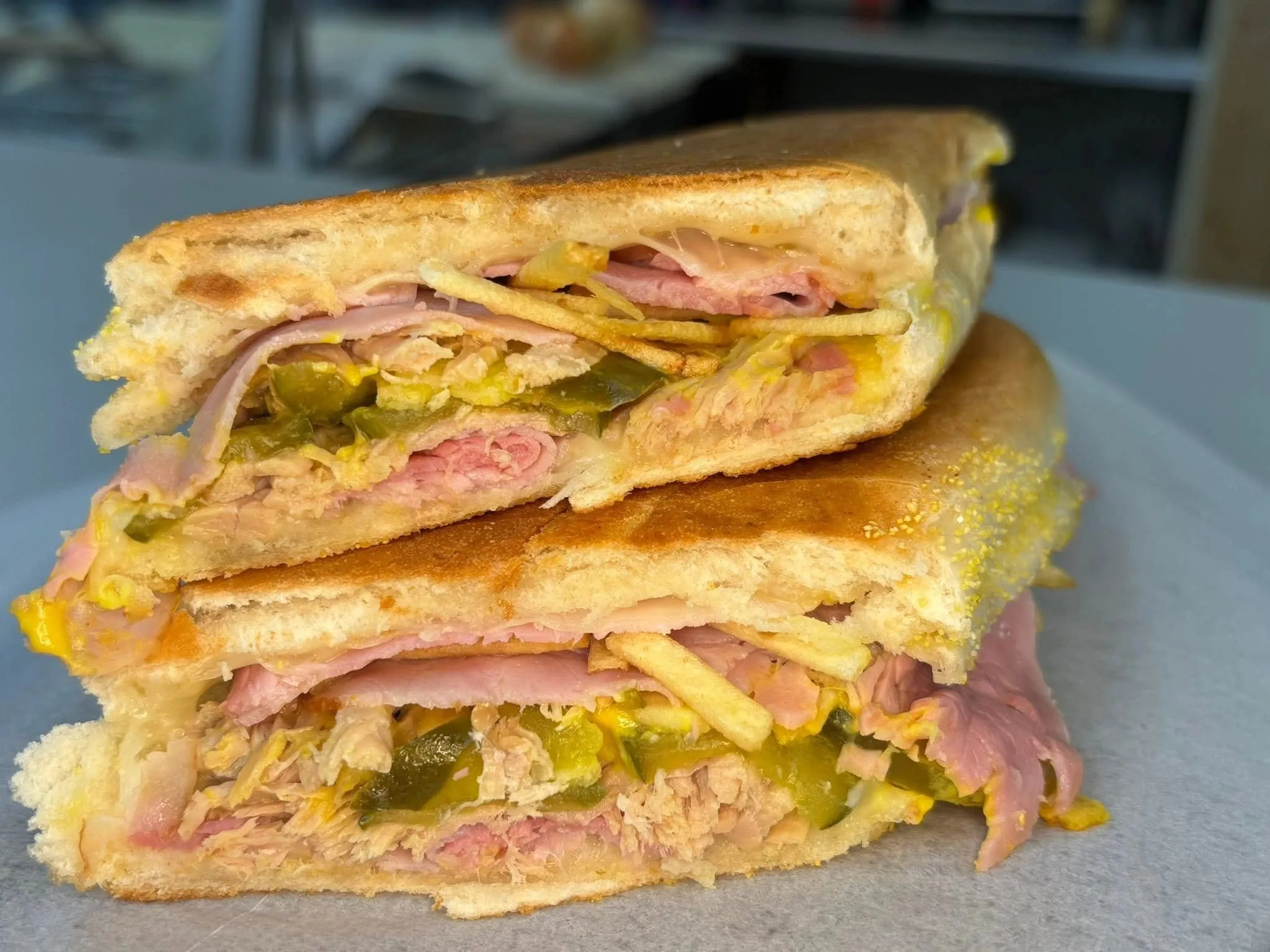 Cuban-style pressed sandwich, cut and stacked, ham and pickles visible