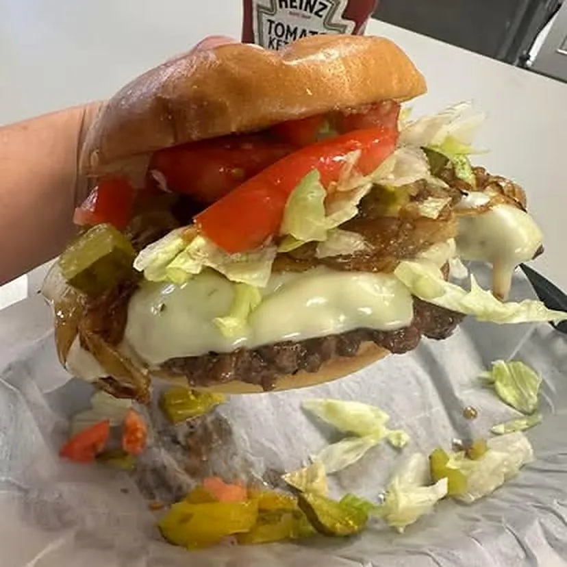 Bacon smash burger with lettuce, tomato, melted cheese, and griddled onions